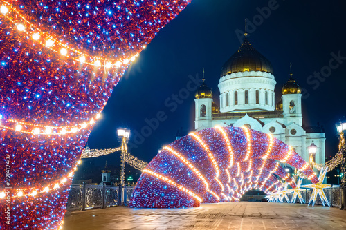 Moscow. Russia. Church of Christ the Saviour on a festive evening. Orthodox Church on the background of Christmas decorations from garlands. Flying luminous stars on the background of the temple.