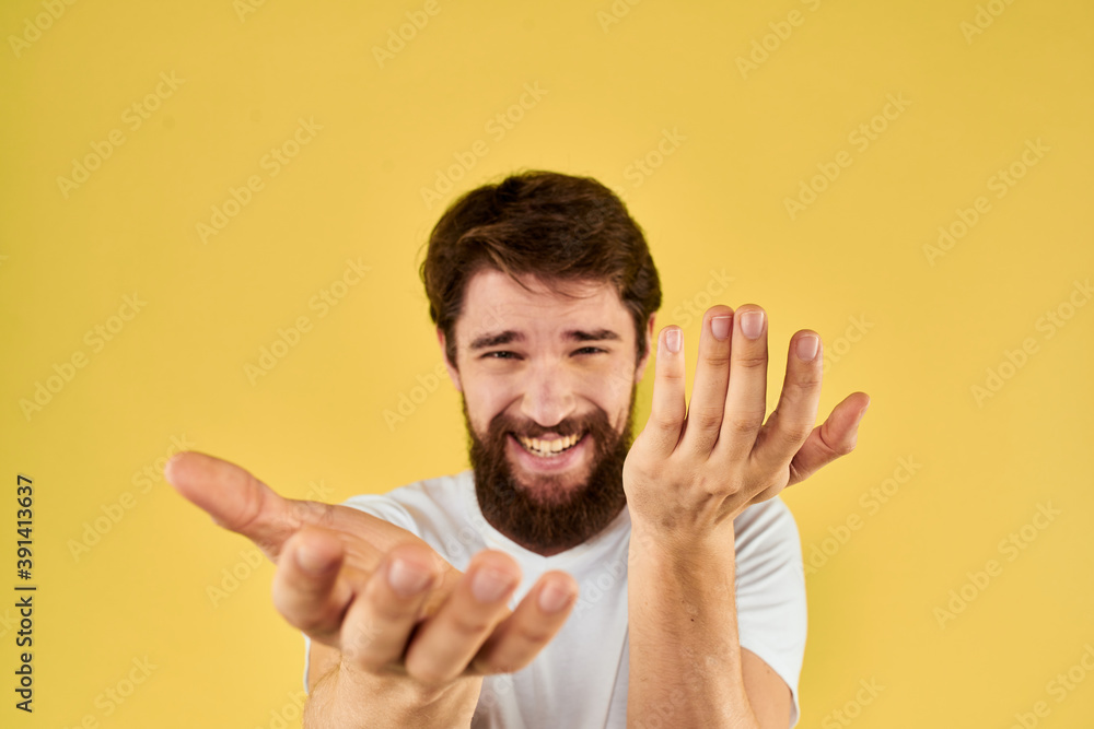 A man in a white t-shirt gestures with his hands lifestyle cropped view yellow background more fun A man in a white t-shirt gestures with his hands lifestyle cropped view yellow background more fun