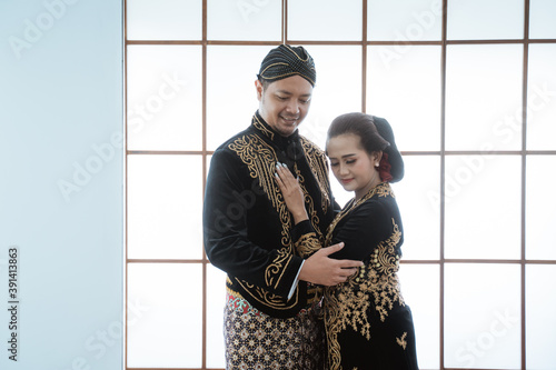 Portrait happy men and women wearing javanese traditional clothes. Couple concept photo standing by the window photo