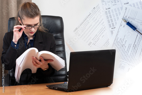 Personal accountant. Girl carefully studies the declaration. Woman next to a laptop. Concept - accountant fills out a 1040 declaration. Individual Income Tax Return. Paying taxes in the USA. photo