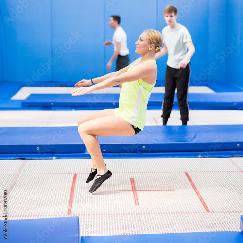 Young sporty woman with friends practicing and jumping in trampoline center © JackF