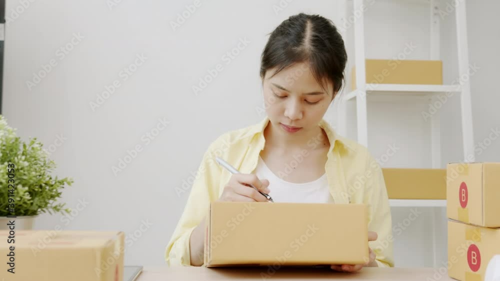 Startup small business concept, young woman owner working and packing on the box to customer at home office, seller prepares the delivery.