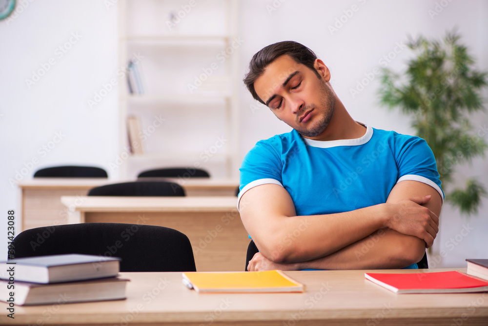 Exhausted male student preparing for the exams in the classroom Exhausted male student preparing for the exams in the classroom