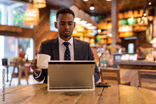Young African businessman using laptop computer at coffee shop