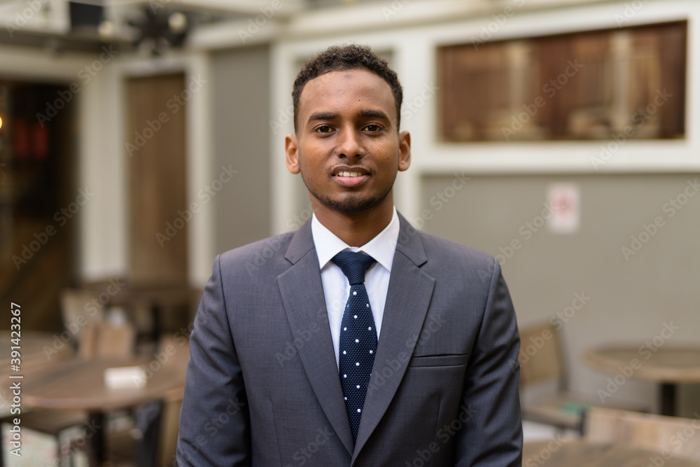 Portrait of young African businessman relaxing outdoors at coffee shop Portrait of young African businessman relaxing outdoors at coffee shop