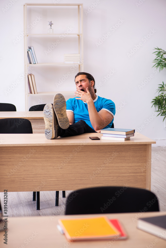 Exhausted male student preparing for the exams in the classroom Exhausted male student preparing for the exams in the classroom