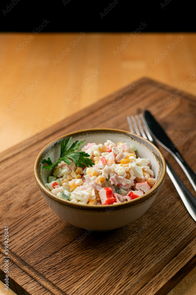 Traditional russian new year salad with boiled rice, canned corn and crab meat in a small bowl on a rustic table Traditional russian new year salad with boiled rice, canned corn and crab meat in a small bowl on a rustic table