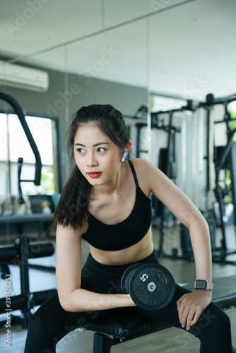 Healthy asian woman exercise with dumbbell in gym.