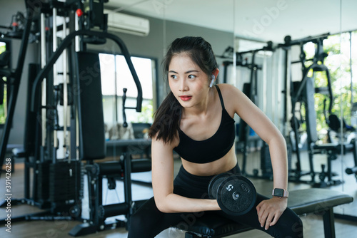 Healthy asian woman exercise with dumbbell in gym.