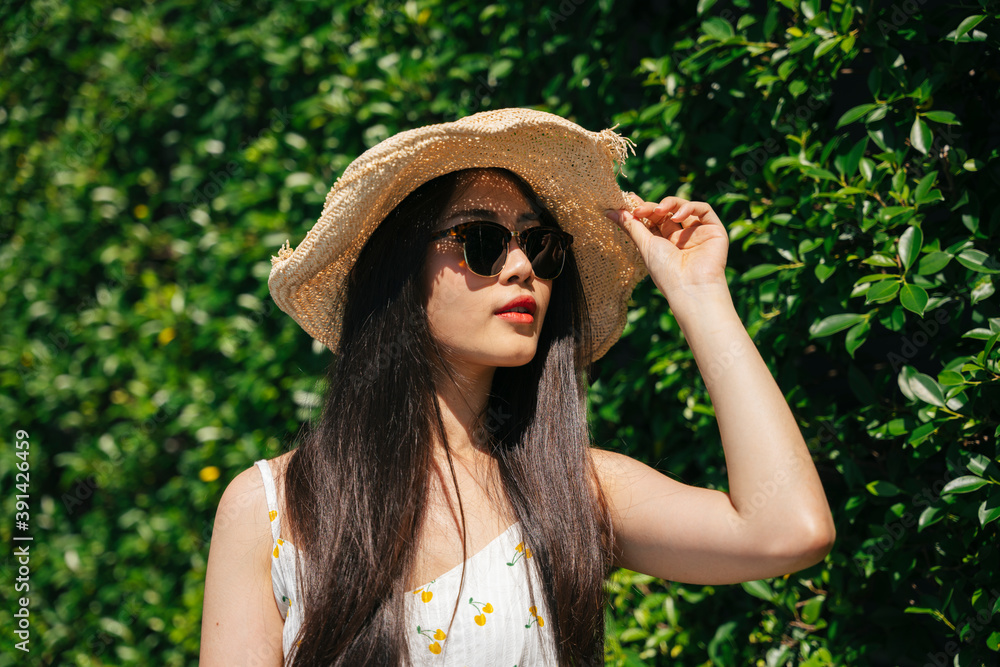 Beautiful asian traveler woman wearing hat and sunglasses on nature background.