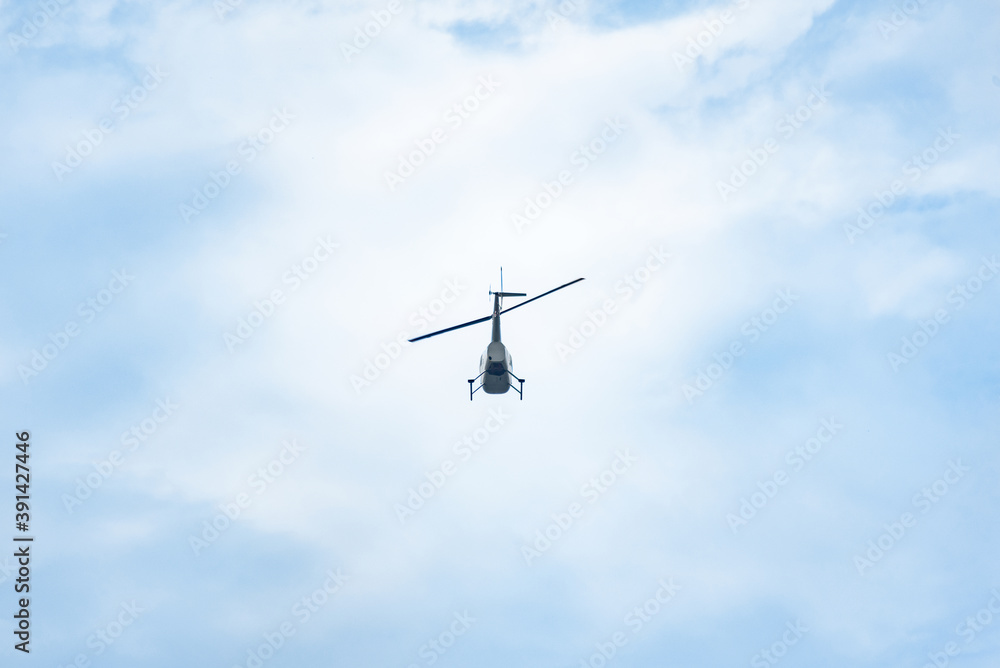 silhouette of a small helicopter flying in the sky