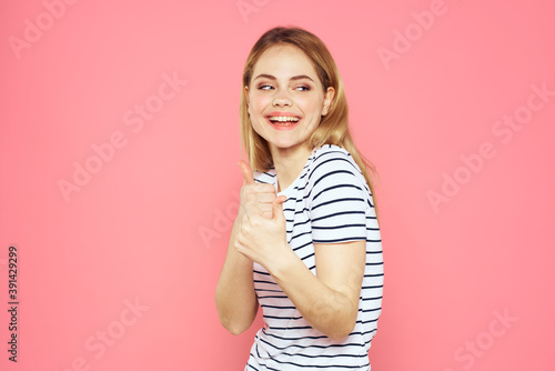 Cheerful woman striped t-shirt lifestyle emotions and gestures with hands pink background