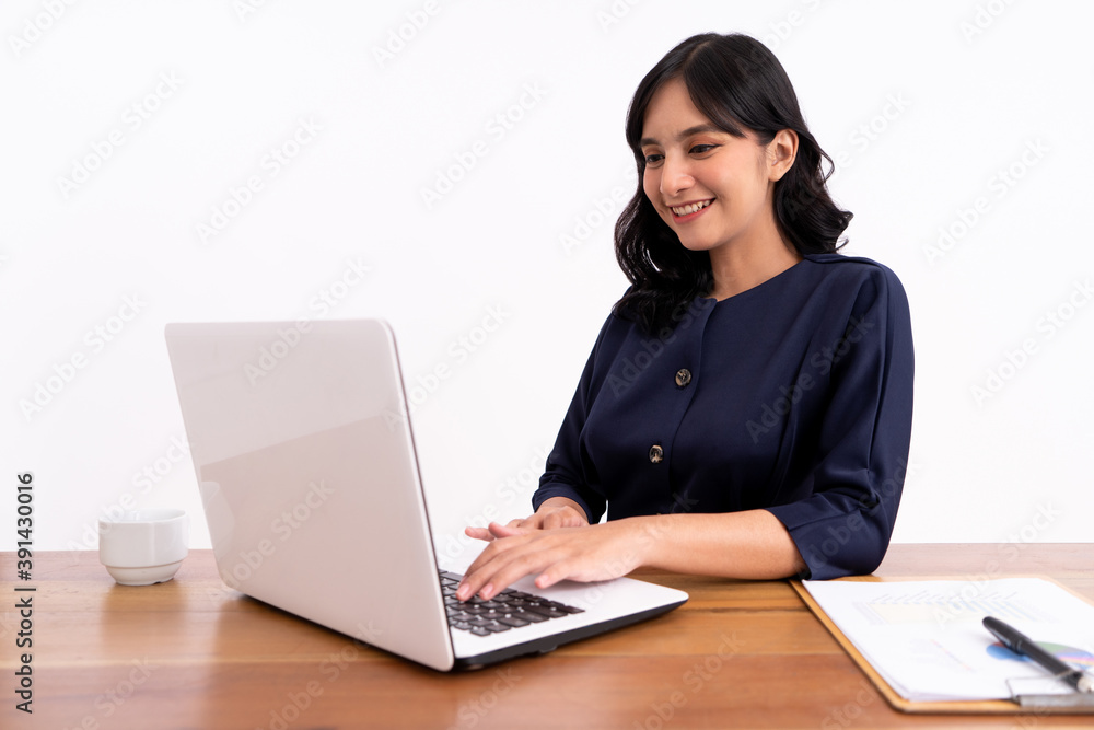Attractive cheerful young business woman working on laptop and smiling while sitting. At her desk modern office Attractive cheerful young business woman working on laptop and smiling while sitting. At her desk modern office