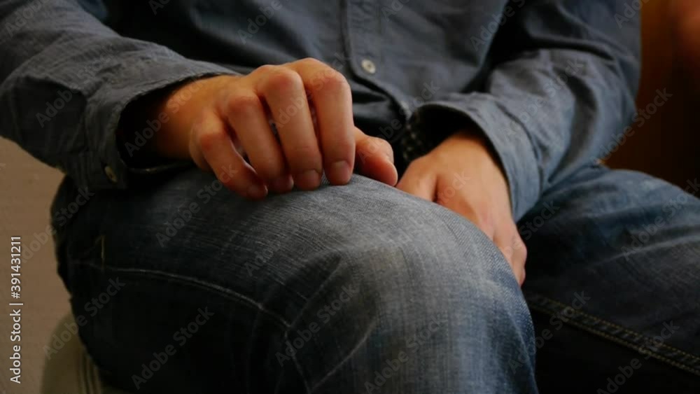 Patient sits in a doctor's waiting room and plays nervously with his hands on his leg Patient sits in a doctor's waiting room and plays nervously with his hands on his leg