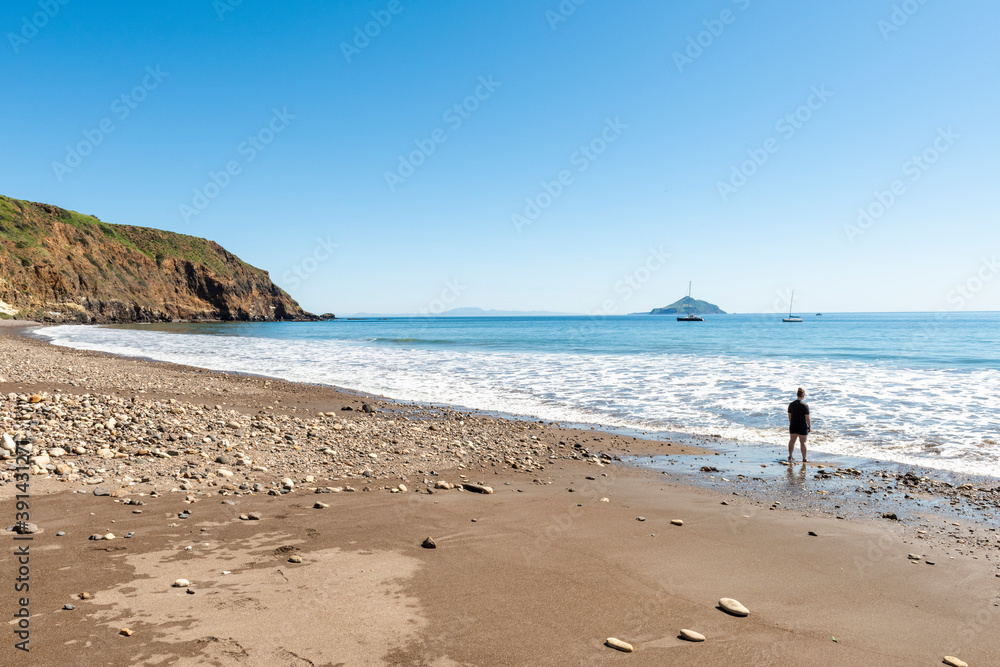 Girl relaxing on beach of Smugglers Cove, Santa Cruz Island, Channel Islands National Park, California