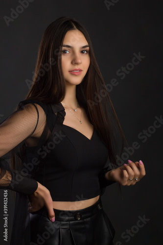 Young beautiful brunette with long hair, posing in black clothes. In a Studio photo