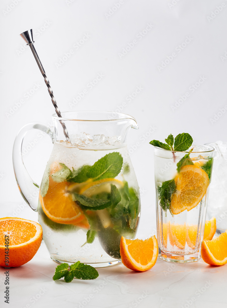 Fototapeta premium Orange and mint lemonade in a jug and glass 