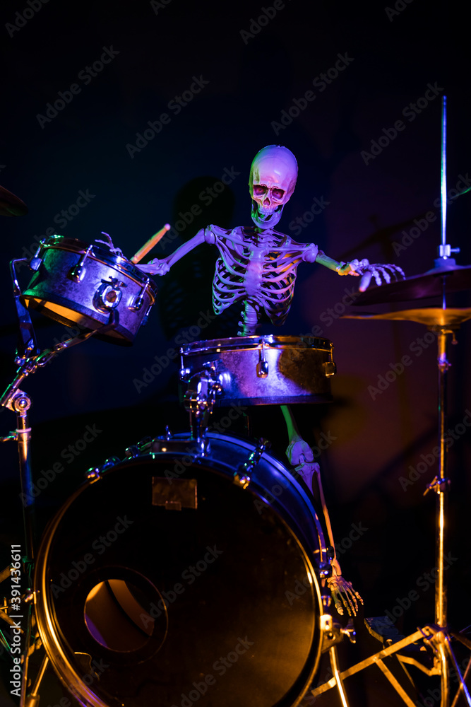 Low point of view skeleton playing drums in the dark