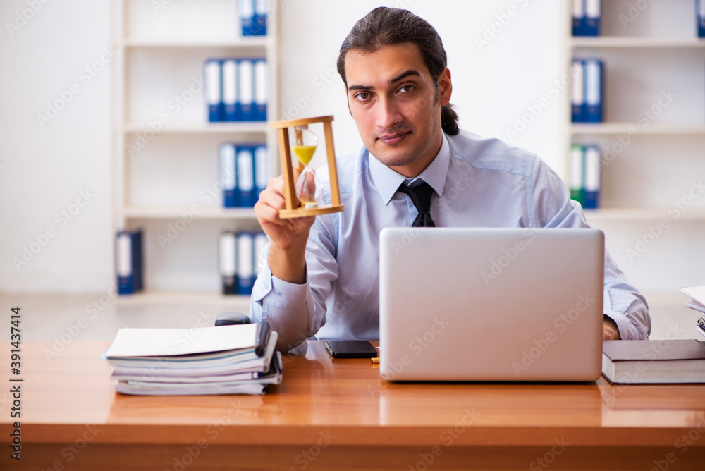 Young male employee in time management concept Young male employee in time management concept