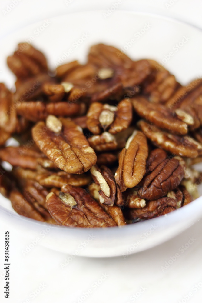 Pecan halves in glass bowl. Isolated on white background. Pecan halves in glass bowl. Isolated on white background.