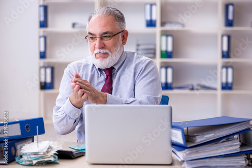 Old male accountant in budget planning concept in the office