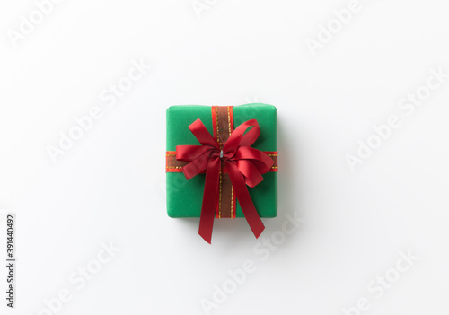 Top view green present gift box with red ribbon on the white table background. Merry christmas and Happy new year theme.