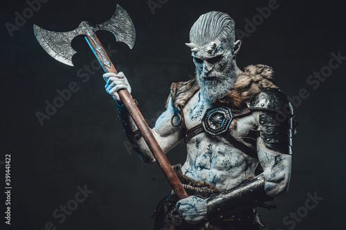 Bringer of the death king with pale skin holding two handed axe and looking down in dark background.