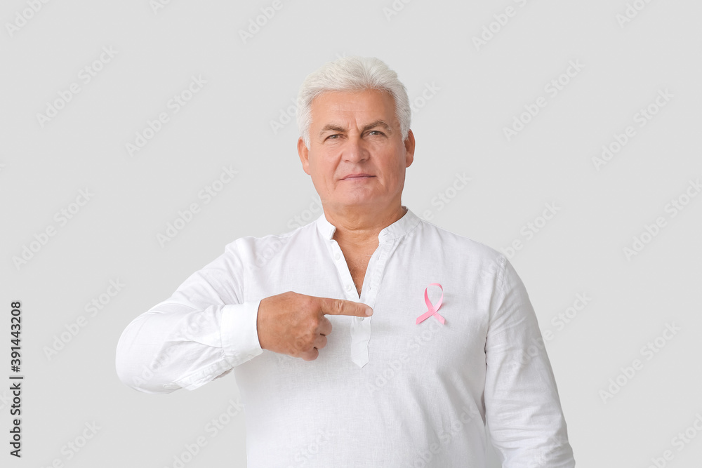 Mature man with pink ribbon on light background. Breast cancer awareness concept Mature man with pink ribbon on light background. Breast cancer awareness concept