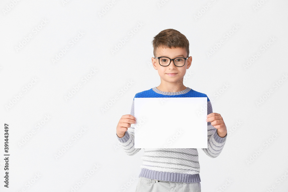 Little boy with blank paper sheet on light background Little boy with blank paper sheet on light background