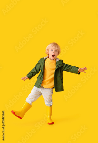 Surprised little boy in autumn clothes on color background