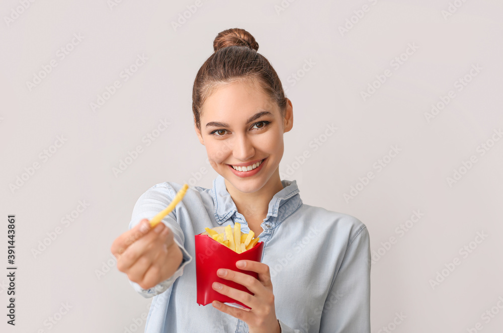 Young woman with french fries on light background Young woman with french fries on light background