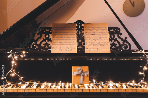 Grand piano with note sheets and Christmas decor in room