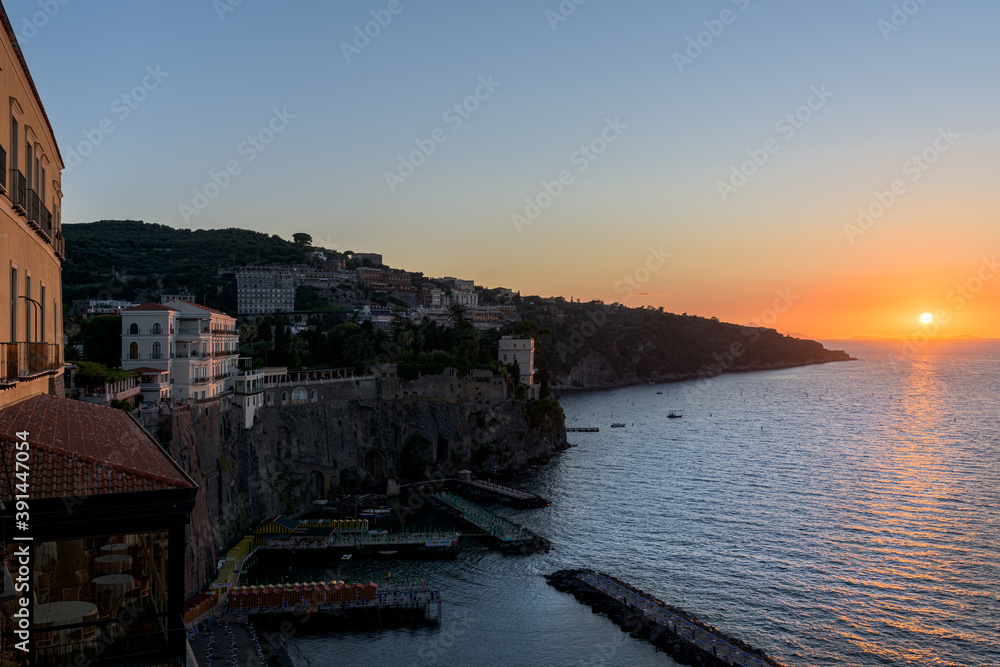 Sunset over Sorrento cliff hanging village, a Unesco world heritage site in Amalfi Coast, Campany, Italy. Mooring port and beach resorts with buildings looking over the Mediterranean Sea