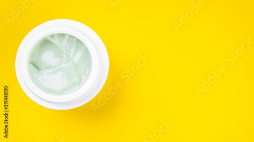 white jar with cream on a yellow background