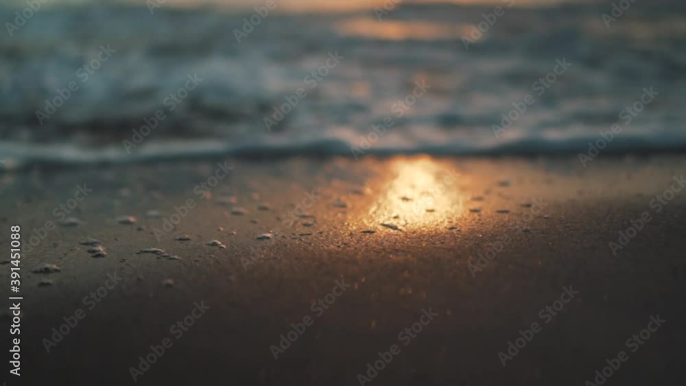 SLOW MOTION of the sea water flooding the reflection of the sunset on the shoreline during golden hour. Close-up with blurry background SLOW MOTION of the sea water flooding the reflection of the sunset on the shoreline during golden hour. Close-up with blurry background