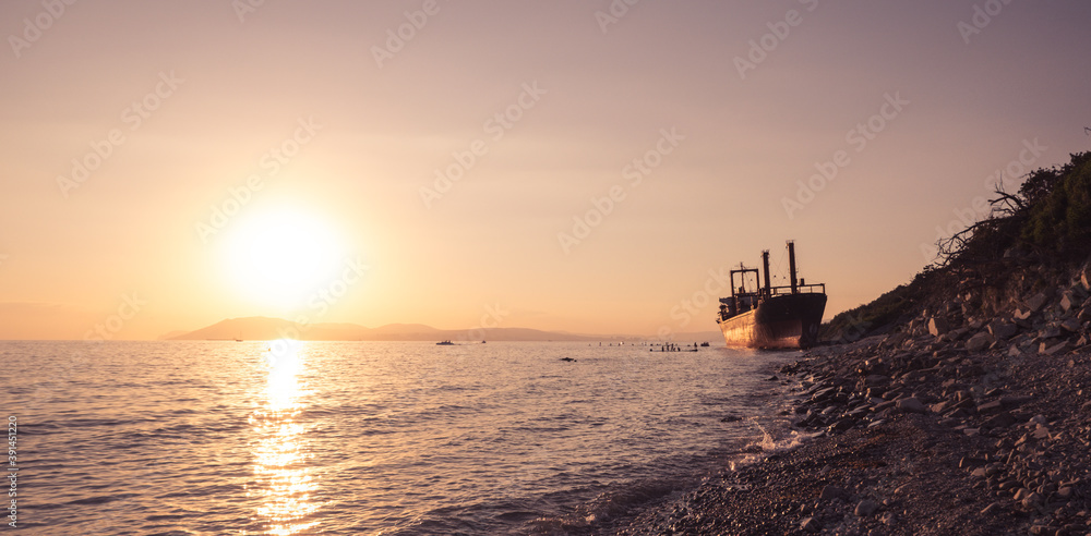 cargo ship running aground. Sunset on the pebbly seashore