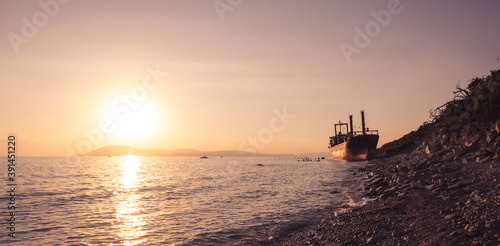 cargo ship running aground. Sunset on the pebbly seashore © Alexey Oblov