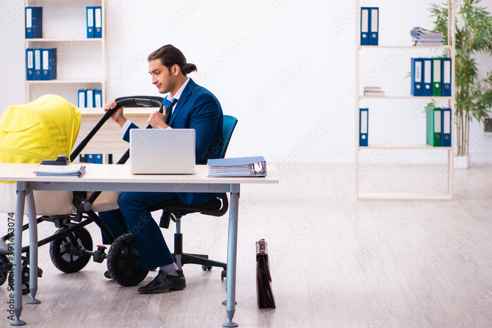 Young male employee looking after kid at workplace Young male employee looking after kid at workplace