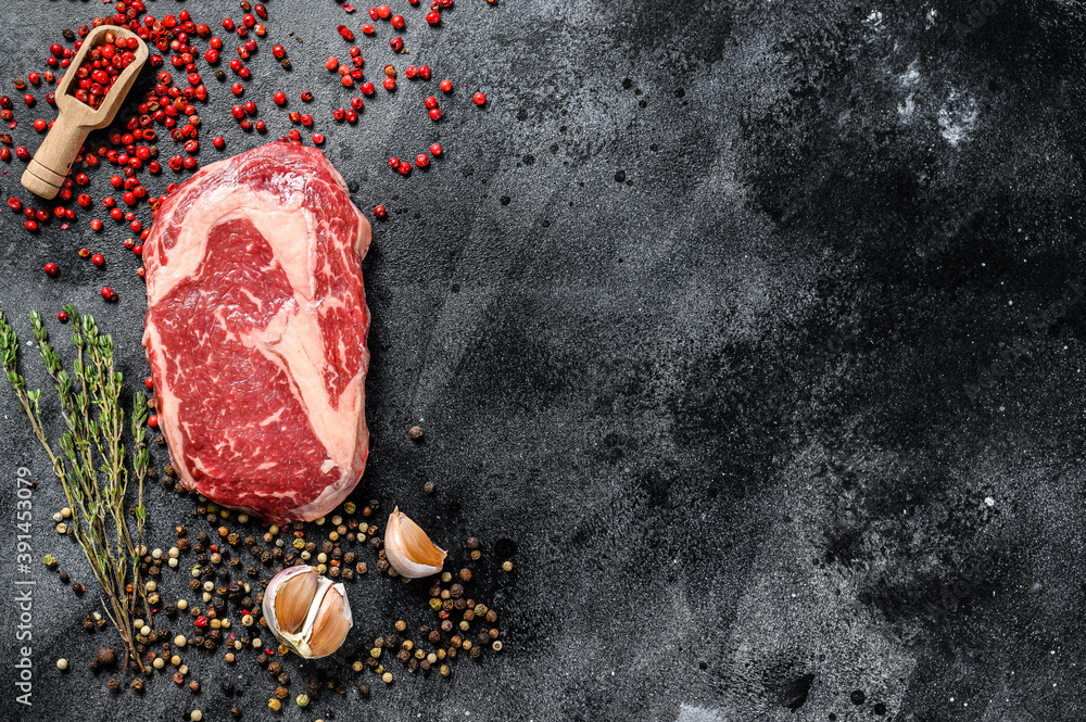 Raw fresh meat Ribeye Steak with seasoning. Rib eye beef steak. black background. top view. Copy space