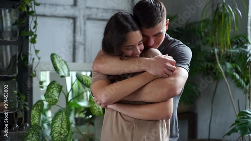 Young man hugging woman from behind. Romantic couple of lovers cuddling at home.