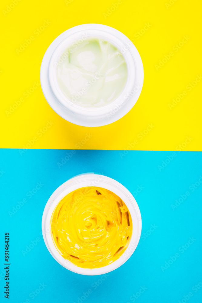 cosmetics bottles with cream on blue and yellow background cosmetics bottles with cream on blue and yellow background