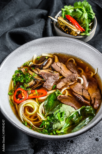 Traditional Vietnamese soup Pho bo with herbs, meat, rice noodles, broth. Black background. Top view