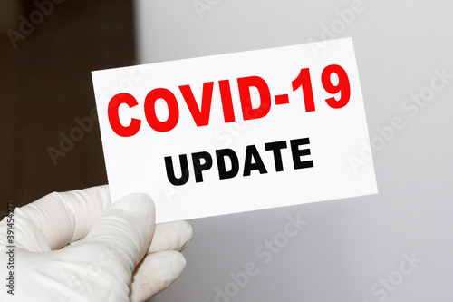 The doctor's hands show the word COVID-19 UPDATE . a gloved hand on a white background. Medical concept. the medicine