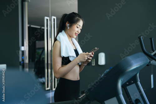 Asian woman choosing song before running on treadmill.
