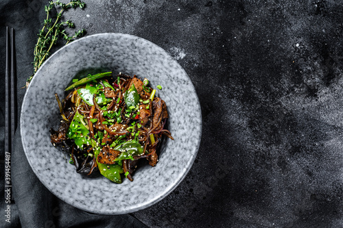 Soba noodles with beef, carrots, onions and sweet peppers. Stir fry wok. Black background. Top view. Copy space