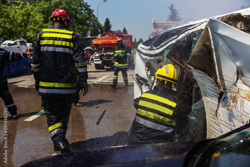 Firemen in action. Firemen extinguishing fire and trying to flip over crashed car in car accident. Firemen in action. Firemen extinguishing fire and trying to flip over crashed car in car accident.