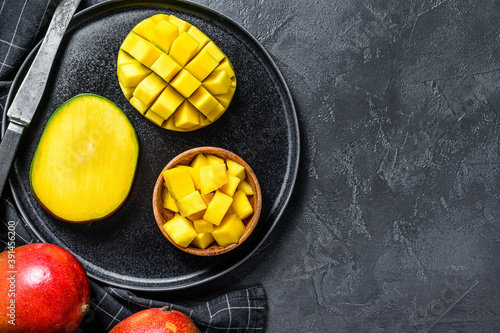 A ripe mango. Cut into cubes tropical fruit. Black background. Top view. Copy space