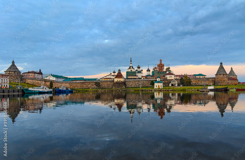 Evening landscape of the Bay of Well-being and the Solovetsky Kremlin with reflection in the water.