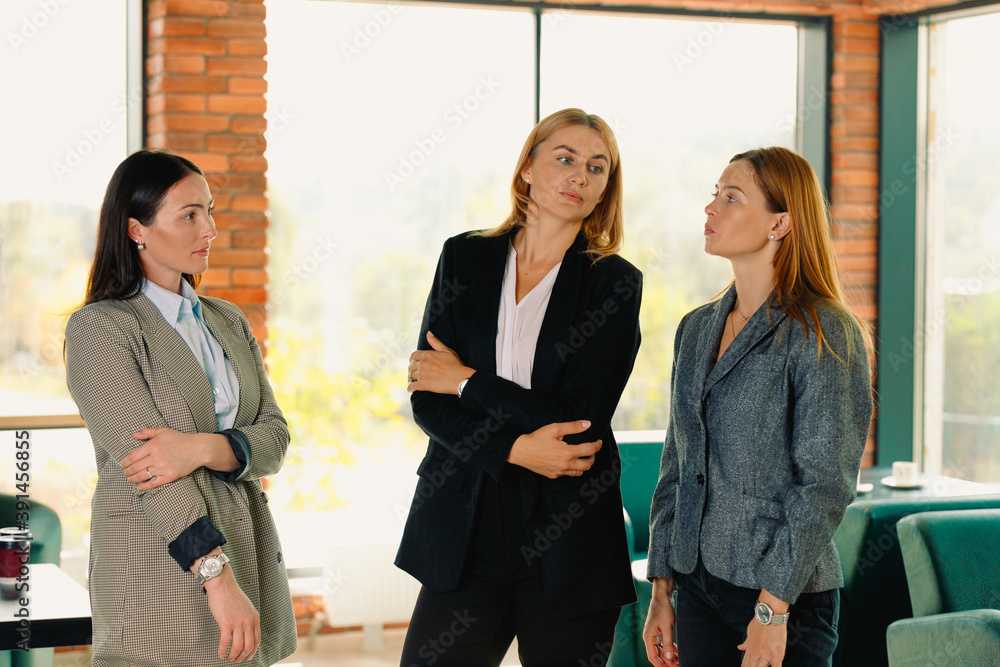 Three business women discussing dry topics in a cafe. Team building concept. Photo against the background of large windows. Three business women discussing dry topics in a cafe. Team building concept. Photo against the background of large windows.