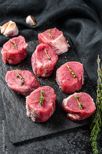 Raw pork medallion steaks with pepper and thyme. black background. Top view